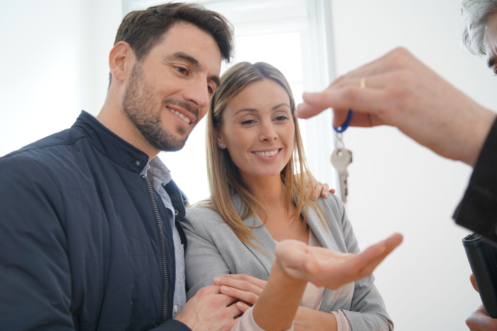 Estate agent handing over keys to happy new home owners