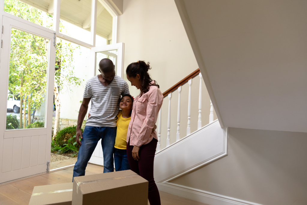 Side view of a mixed race couple and their young daughter standing in the hallway of their new home with arms around each other